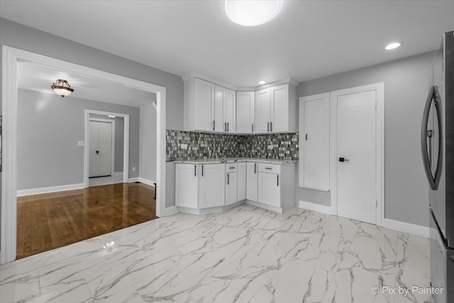 kitchen featuring white cabinets, stainless steel refrigerator, and tasteful backsplash