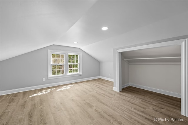 additional living space with light hardwood / wood-style floors and vaulted ceiling