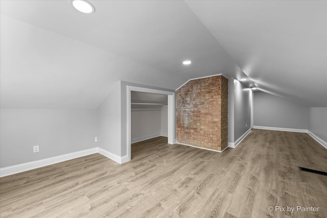 bonus room featuring light wood-type flooring and vaulted ceiling