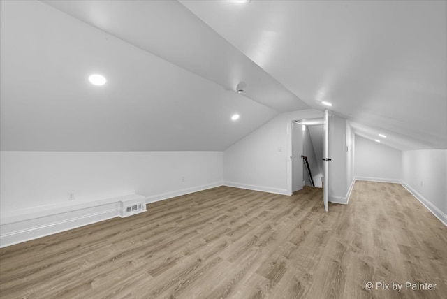 additional living space featuring lofted ceiling and light wood-type flooring