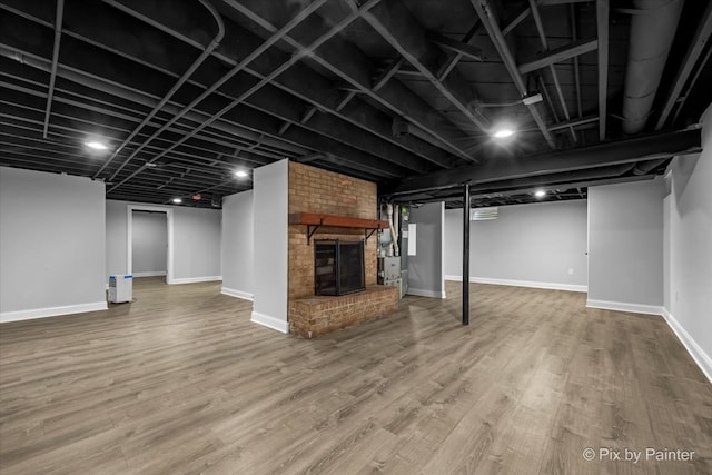 basement with a brick fireplace and wood-type flooring