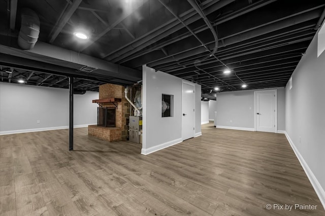 basement featuring hardwood / wood-style floors and a brick fireplace