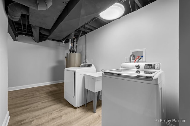 washroom with wood-type flooring, water heater, and washing machine and dryer