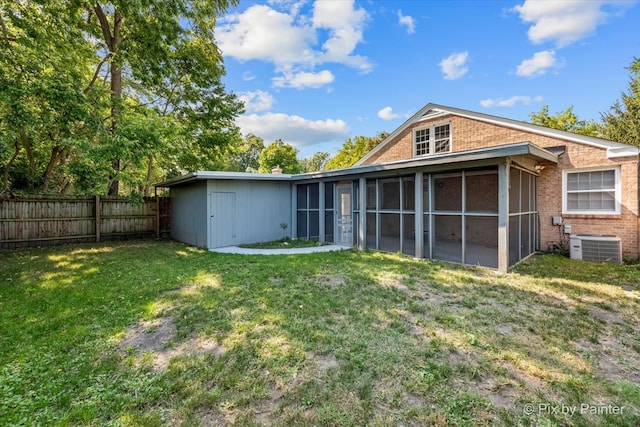 back of property featuring a sunroom, central AC unit, and a lawn