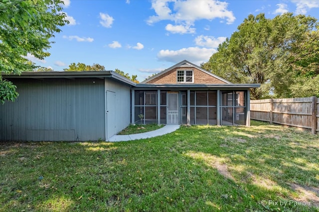 back of house featuring a sunroom and a lawn