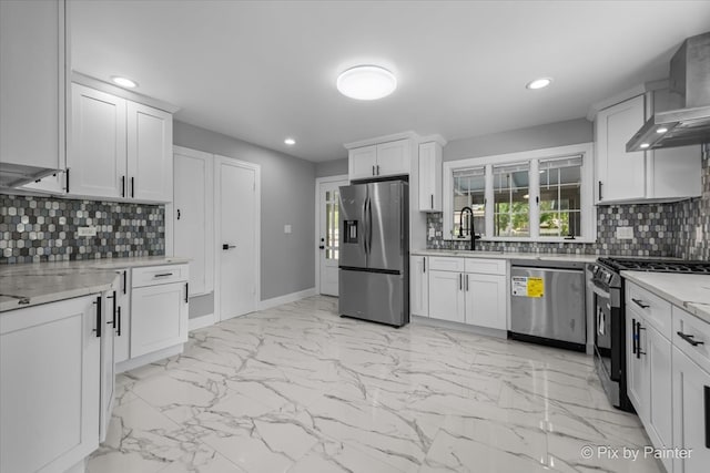 kitchen with white cabinets, backsplash, wall chimney exhaust hood, stainless steel appliances, and sink