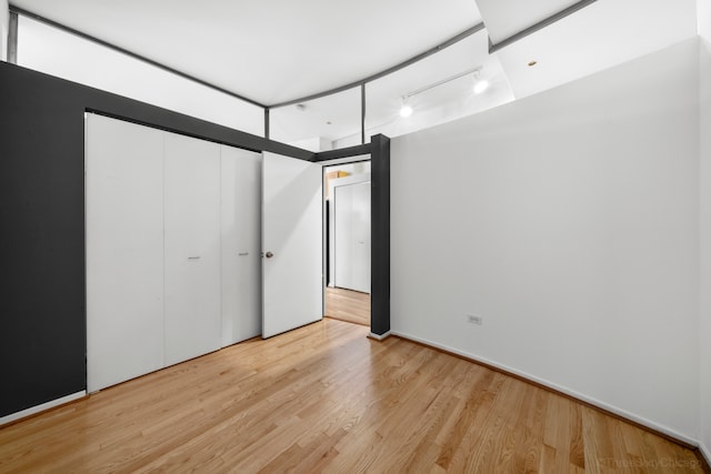 unfurnished bedroom with light hardwood / wood-style floors and track lighting