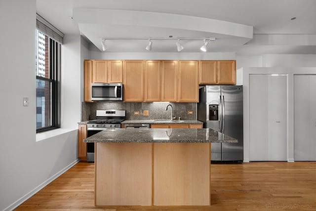 kitchen featuring dark stone counters, appliances with stainless steel finishes, a kitchen island, and sink