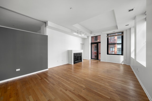 unfurnished living room featuring a raised ceiling and hardwood / wood-style floors