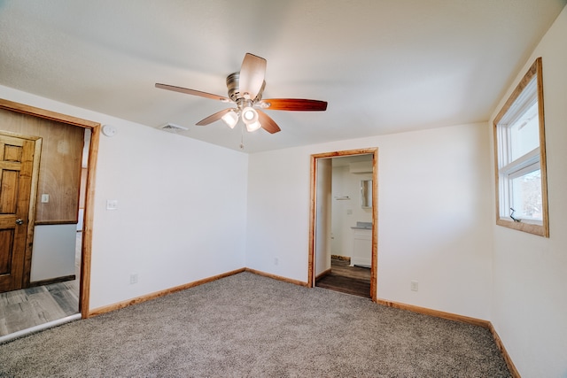 spare room with dark colored carpet and ceiling fan