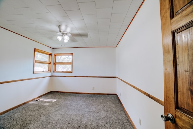 carpeted spare room with ceiling fan and crown molding