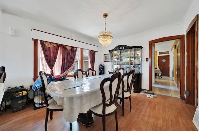 dining room featuring a notable chandelier, light wood-type flooring, and crown molding