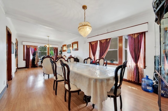 dining area with light wood-type flooring, ornamental molding, and a notable chandelier