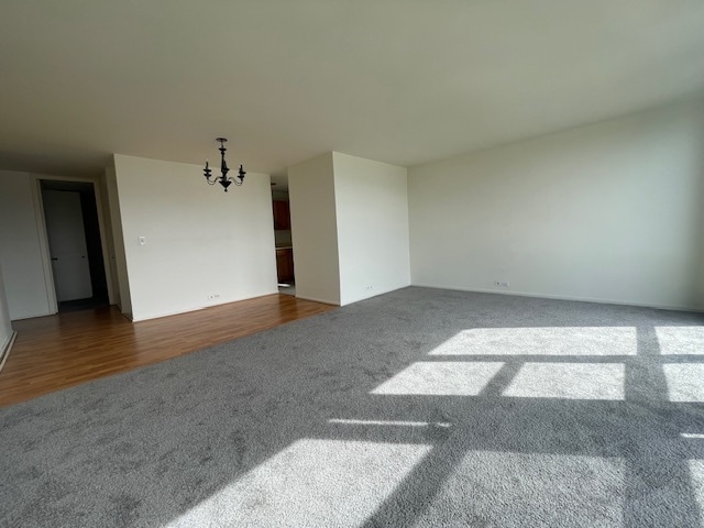 spare room featuring a notable chandelier and dark wood-type flooring