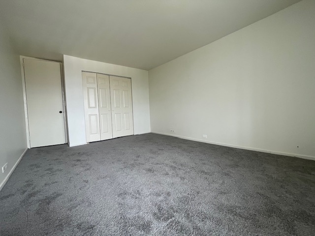 unfurnished bedroom featuring a closet and dark carpet