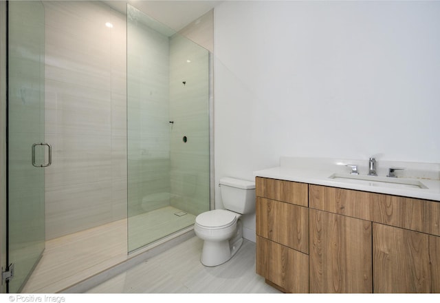 bathroom featuring vanity, toilet, and a shower with shower door