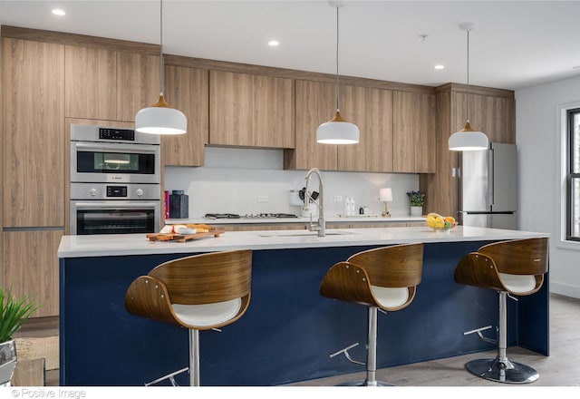 kitchen with a kitchen breakfast bar, a center island with sink, sink, and stainless steel appliances