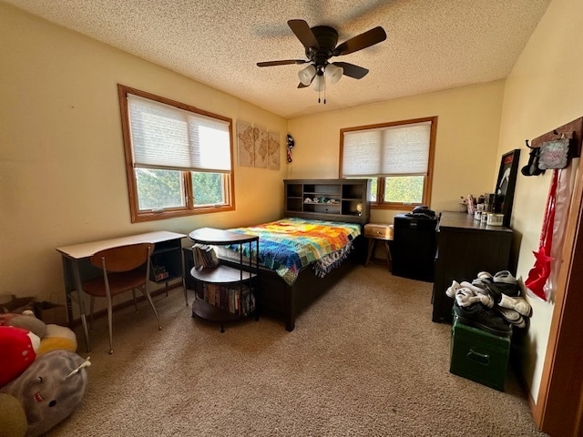 carpeted bedroom featuring ceiling fan, a textured ceiling, and multiple windows