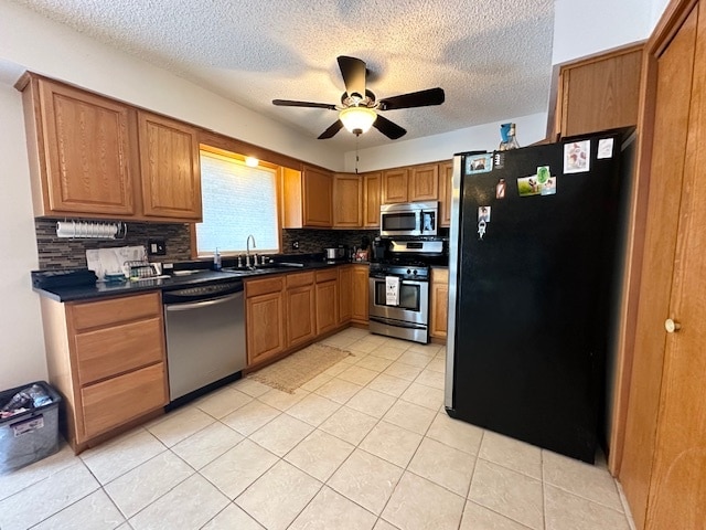 kitchen with ceiling fan, sink, light tile patterned floors, appliances with stainless steel finishes, and decorative backsplash