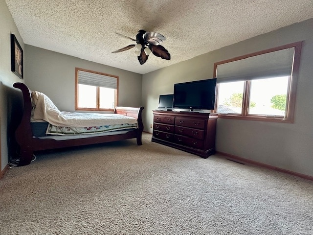 bedroom featuring a textured ceiling, light carpet, and ceiling fan