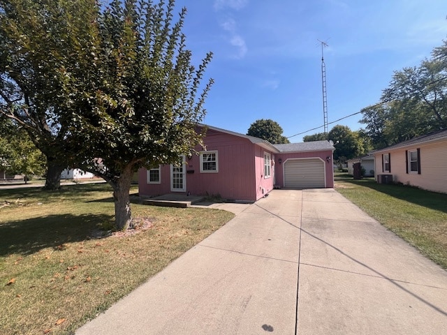 view of front of property with a garage, a front lawn, and central AC