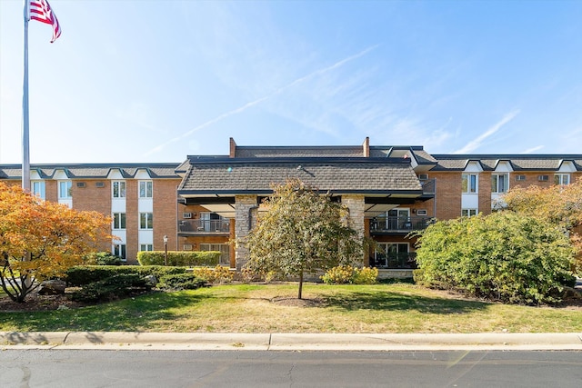 view of front of property featuring a balcony and a front lawn