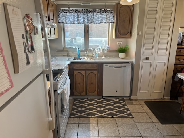 kitchen featuring white refrigerator, light tile patterned flooring, range, and stainless steel dishwasher