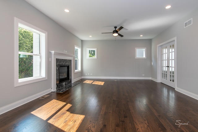 unfurnished living room with a wealth of natural light, a premium fireplace, ceiling fan, and dark hardwood / wood-style flooring