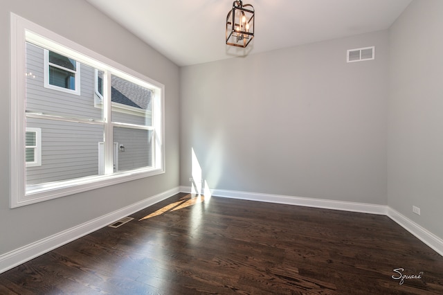 empty room with an inviting chandelier and dark wood-type flooring