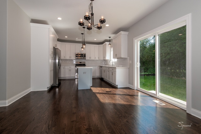 kitchen featuring white cabinets, hanging light fixtures, stainless steel appliances, dark hardwood / wood-style floors, and a center island