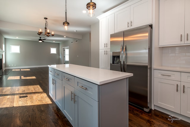 kitchen featuring tasteful backsplash, a kitchen island, dark wood-type flooring, stainless steel fridge with ice dispenser, and ceiling fan with notable chandelier