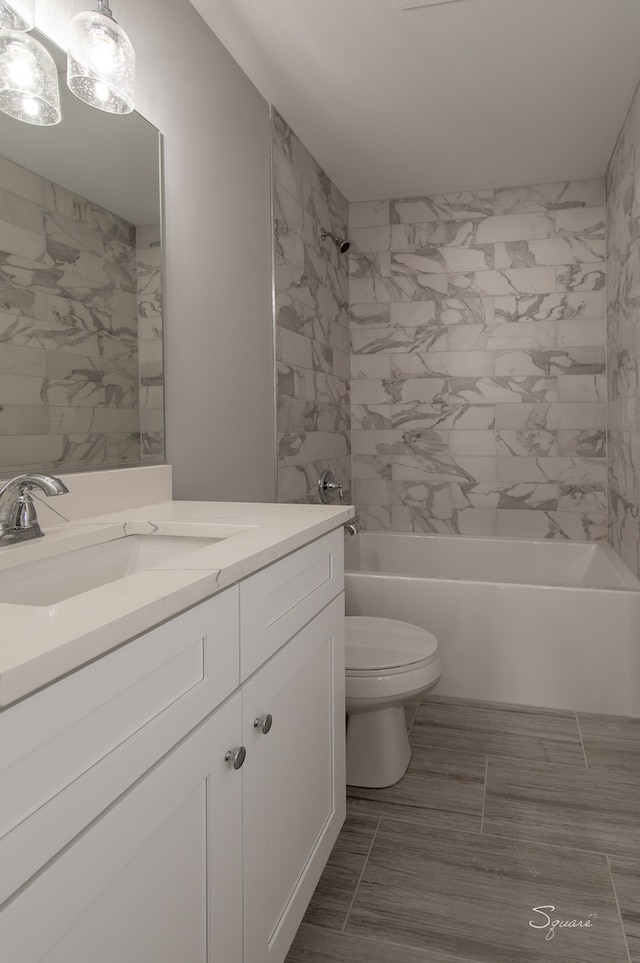 full bathroom featuring tiled shower / bath combo, vanity, and toilet