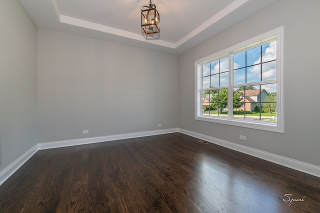 empty room with an inviting chandelier, dark wood-type flooring, and a healthy amount of sunlight