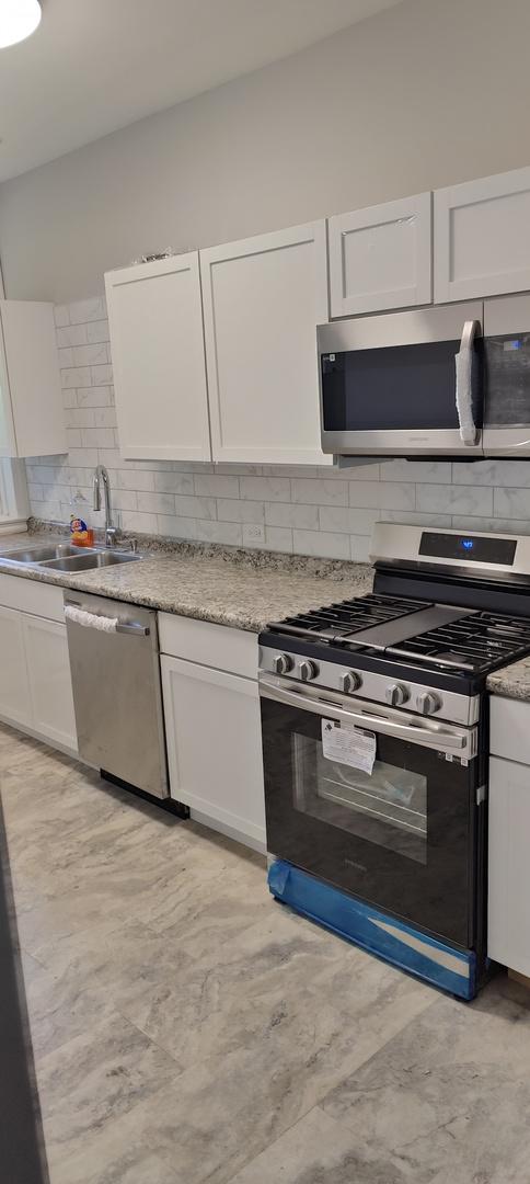 kitchen featuring tasteful backsplash, white cabinetry, sink, and appliances with stainless steel finishes