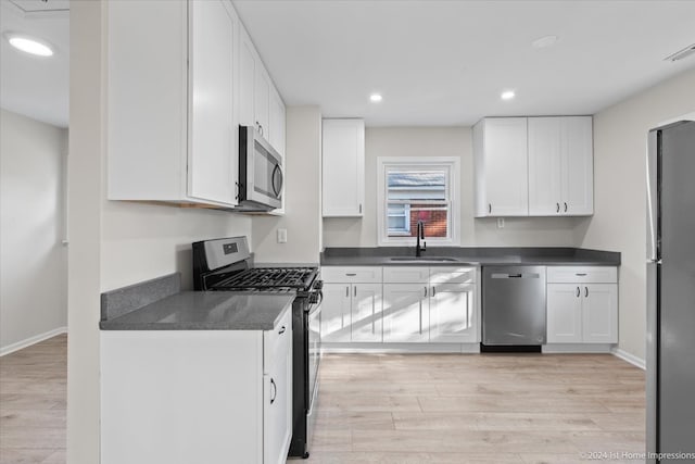 kitchen featuring stainless steel appliances, light wood-type flooring, sink, and white cabinetry