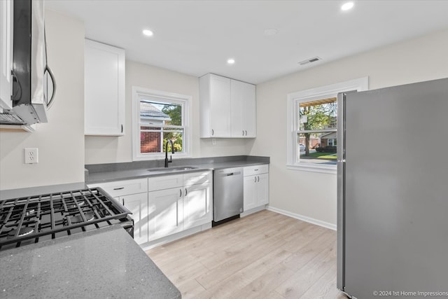 kitchen featuring appliances with stainless steel finishes, a healthy amount of sunlight, white cabinetry, and sink