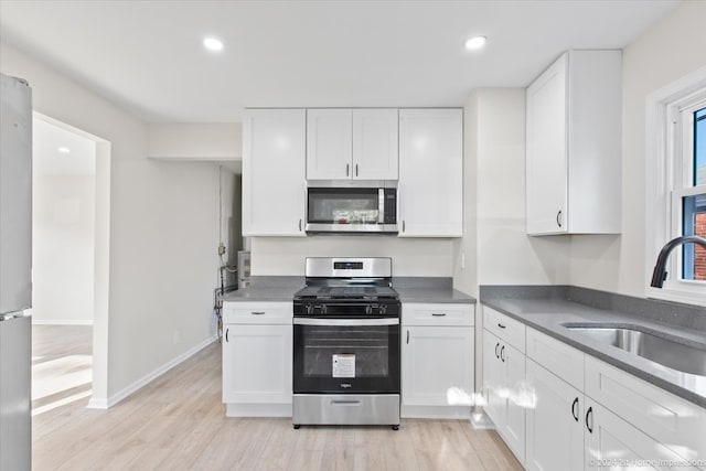 kitchen featuring sink, appliances with stainless steel finishes, light hardwood / wood-style floors, and white cabinetry