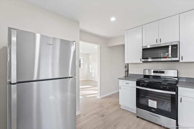 kitchen with stainless steel appliances, light hardwood / wood-style floors, and white cabinetry