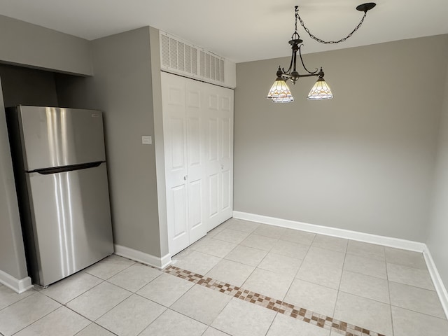 kitchen with decorative light fixtures, light tile patterned floors, stainless steel refrigerator, and a chandelier