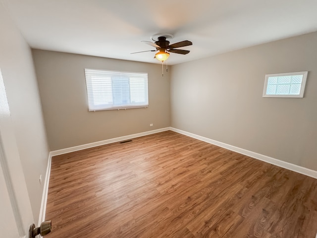 spare room with a wealth of natural light, ceiling fan, and wood-type flooring