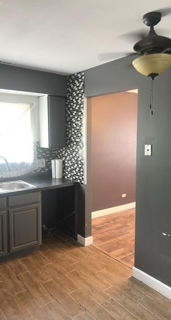 1249 Cunningham Dr Unit 3E, Calumet City, IL 60409 - kitchen with a sink, wood finished floors, backsplash, baseboards, and dark countertops