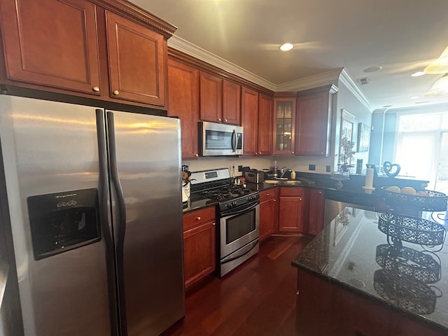 kitchen featuring sink, stainless steel appliances, dark hardwood / wood-style flooring, ornamental molding, and dark stone countertops