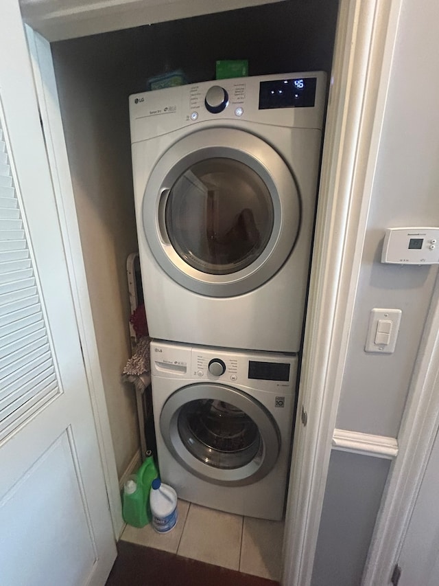 clothes washing area with stacked washer and dryer and tile patterned floors