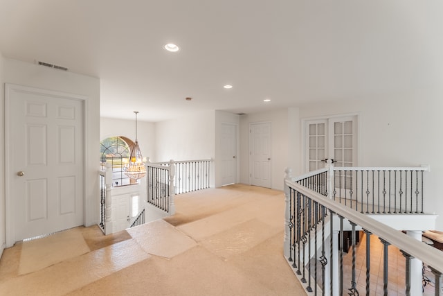 corridor with french doors, carpet, and a chandelier