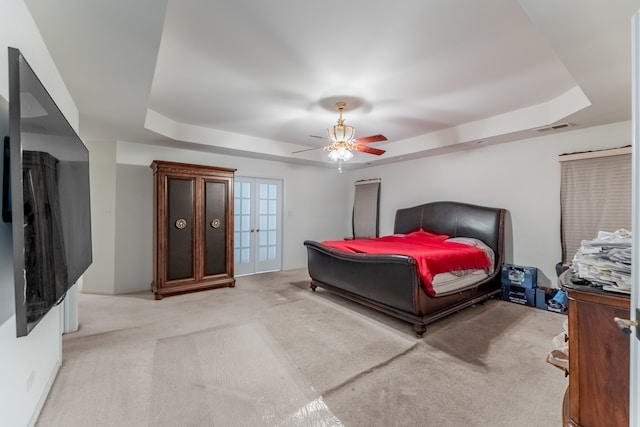 carpeted bedroom featuring a raised ceiling and ceiling fan