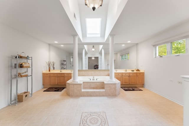 bathroom featuring vanity, tile patterned floors, a skylight, and tiled tub