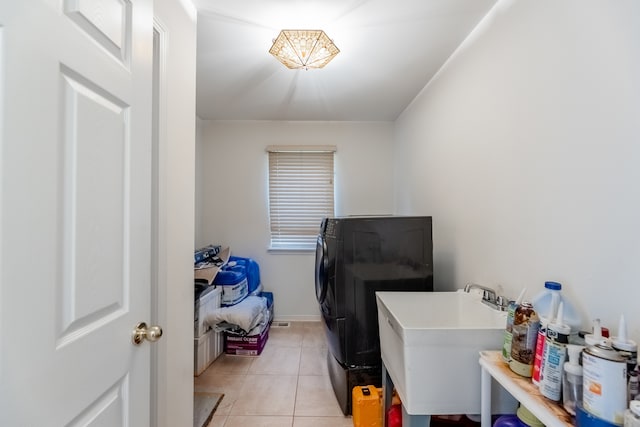 laundry room featuring washer and dryer, sink, and light tile patterned floors