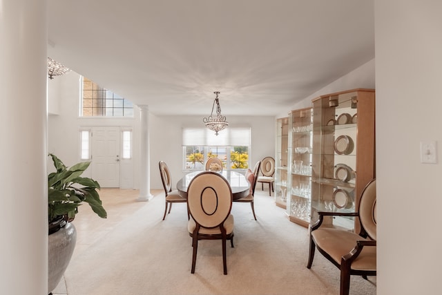 dining room featuring decorative columns, light carpet, and a chandelier