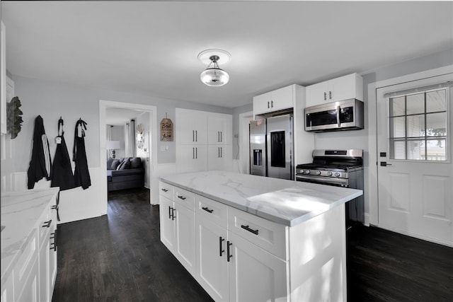 kitchen with light stone counters, a center island, dark hardwood / wood-style floors, white cabinets, and stainless steel appliances