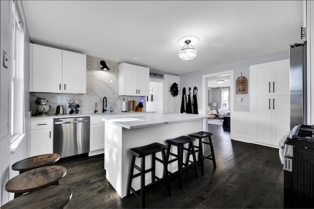 kitchen featuring dark hardwood / wood-style flooring, white cabinetry, a kitchen island, and stainless steel dishwasher